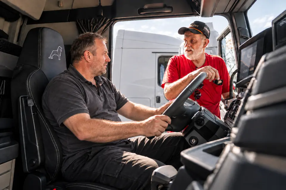 Zwei Männer in einer Lkw-Kabine sprechen über die Bedienung des Fahrzeugs