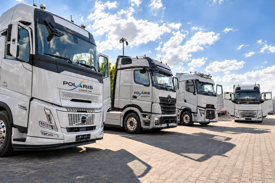 Eine Reihe hellgrauer Lkw mit Polaris-Schriftzug auf dem Betriebshof